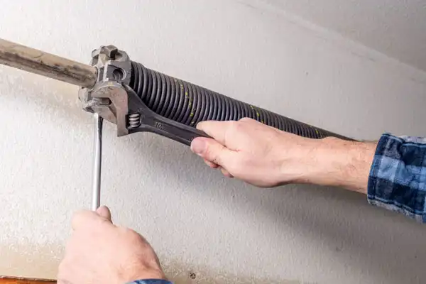 A [account_name] technician installing a garage door spring
